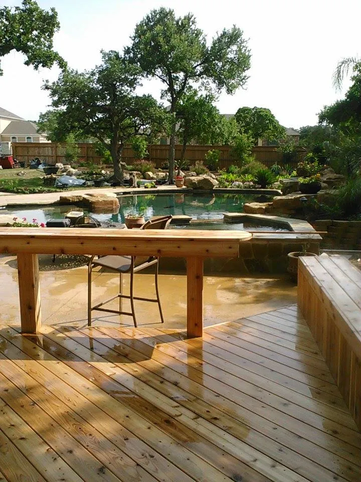 Stained deck with built in bar height seating overlooking a natural rock pool and waterfall