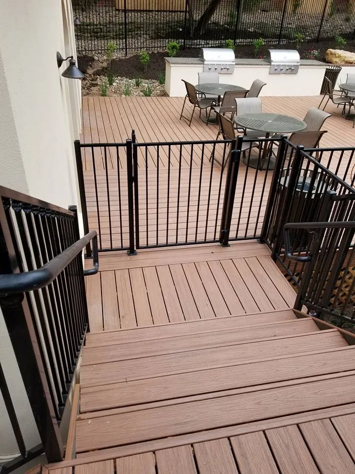 Large composite deck with two built in grill stations, dining sets and black metal railings and stairs
