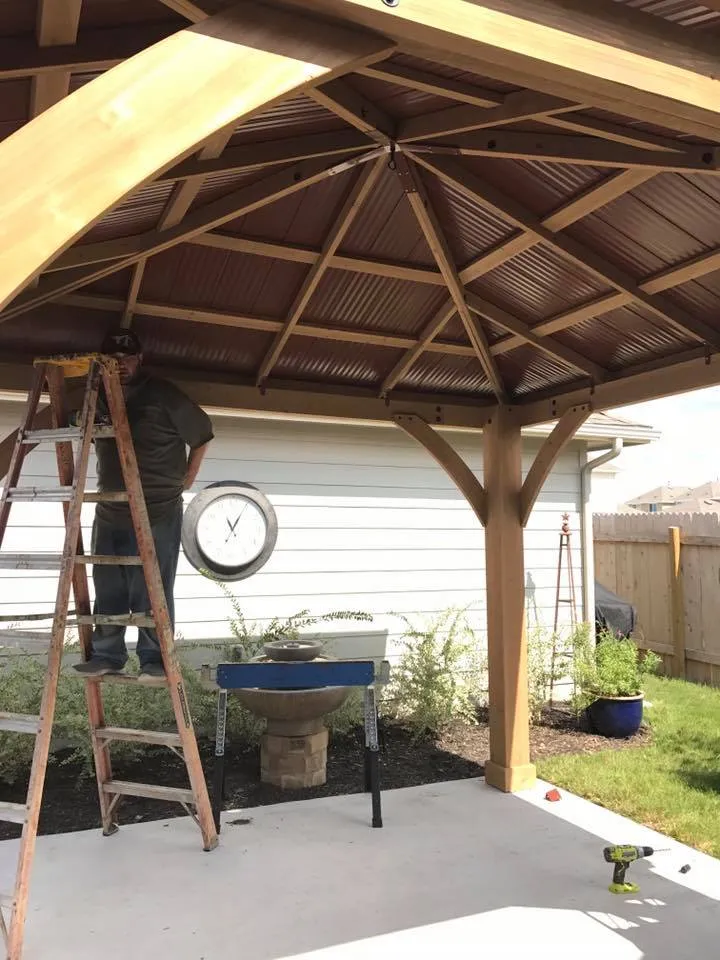 Carpenter finishing the underside of an octagonal cedar gazebo roof with exposed rafters