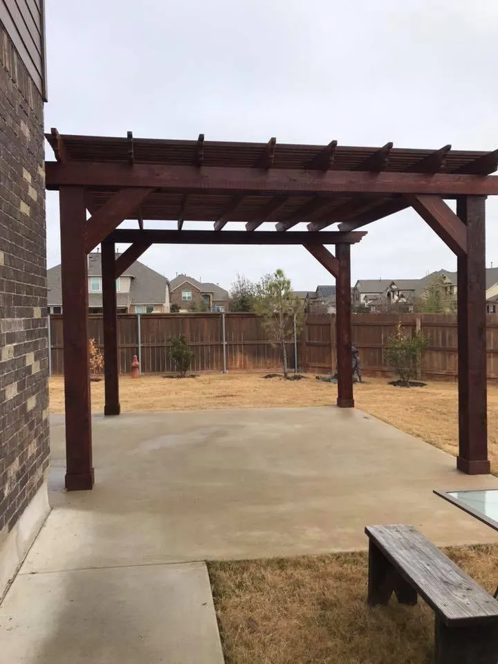 Dark stained cedar pergola on a new concrete patio slab in a suburban backyard